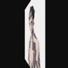 a naked man with tattoos on his body is standing in a cube .
