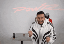 a man in a white adidas hoodie stands in front of a wall that says powz