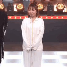 a woman in pajamas stands in front of a microphone with a sign that says ' aa ' on it