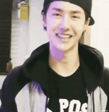 a young man wearing a black hat and a black shirt is smiling .
