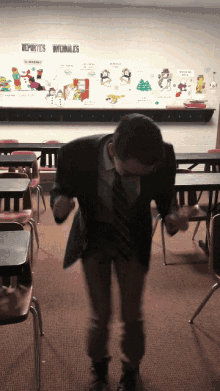 a man in a suit and tie is dancing in front of a wall that says deportes