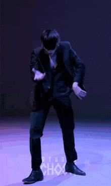 a man in a suit is dancing on a stage in front of a studio choice logo