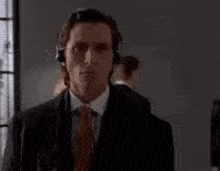 a man in a suit and tie is wearing headphones and standing in a room .