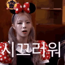 a woman wearing a minnie mouse headband and polka dot sleeves is making a funny face .