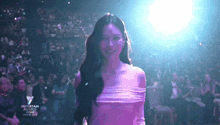 a woman in a purple dress is standing in front of a crowd at an entertainment awards event