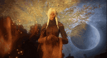 a woman stands in front of a tree and a moon