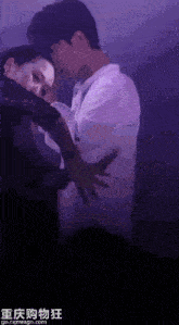 a man is hugging a woman in a dark room with chinese writing on the bottom