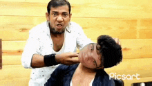 a man is putting his hand on another man 's neck while making a funny face .