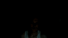 a man in a white tank top is smiling in a dark room