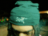 a person wearing a green hat with the letter a embroidered on it
