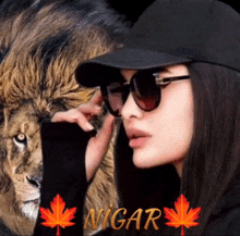a woman wearing sunglasses and a black hat is standing in front of a lion and the word nigar is on the bottom
