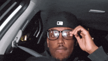 a man wearing a black hat and glasses is sitting in a car