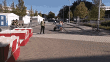a woman pushing a cart down a street with a sign that says ' sd ' on it