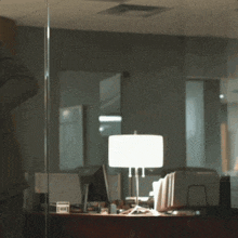 a man in a suit stands in front of a desk with a lamp