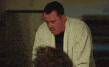 a man in a white robe looks at the camera with a surprised look on his face