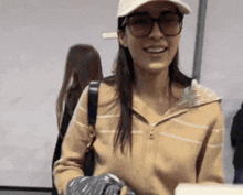a woman wearing a hat and glasses is smiling