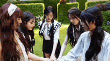a group of girls are holding hands in a circle