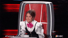 a woman is sitting in a chair with a nbc logo in the corner