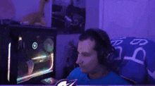 a man wearing headphones is sitting in front of a computer monitor in a dark room .