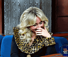 a woman laughs while wearing a leopard print jacket