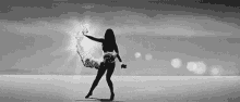 a black and white photo of a woman in a bikini dancing on the beach .