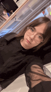 a woman wearing glasses and a black shirt is taking a selfie