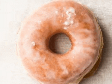 a close up of a glazed doughnut on a white surface .