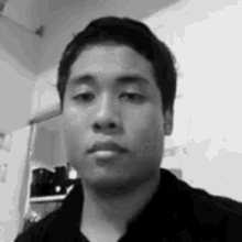 a black and white photo of a man taking a selfie in a room .
