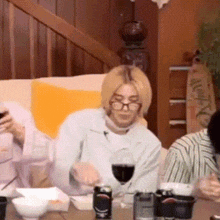 a woman is sitting at a table with a glass of wine and bowls of food .