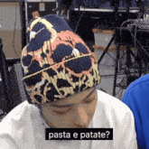 a person wearing a beanie with the words pasta e patate on the bottom