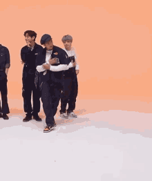 a group of young men are dancing together on a white surface .