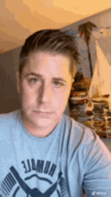 a man wearing a blue shirt is taking a selfie in a room .