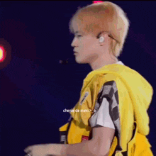 a man wearing a yellow life vest and ear buds is standing on a stage .