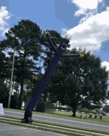 a purple air dancer with a smiling face is standing in a parking lot