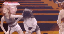 a group of women are dancing on a stage in front of a mnet logo .