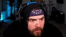 a man with a beard wearing headphones and a purple bandana on his head