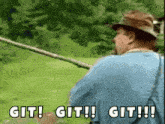 a man in a blue shirt is holding a fishing rod and says git git git !!!