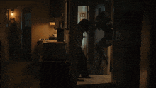 a person standing in a dark room with a microwave and a refrigerator