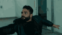 a man with a beard is wearing a black leather jacket and black shirt .