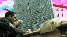a man and a woman are standing in front of a building with birds flying overhead