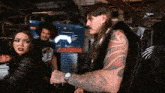 a man with a tattoo on his arm stands in front of a sign that says " controls "