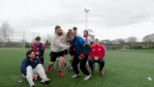 a group of young men are playing a game on a soccer field with one man wearing a hoodie that says levis
