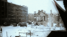 a black and white photo of a snowy area with a few buildings in the background