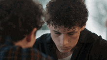 a man with curly hair is looking down at another man 's face