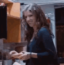 a woman is standing in a kitchen smiling and looking at the camera .