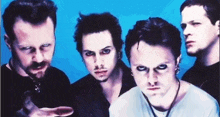 a group of men are posing for a picture in front of a blue background and looking at the camera .