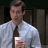 a man in a suit and tie is holding a cup with a smiley face on it