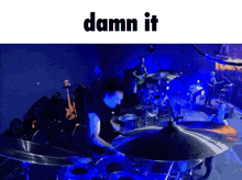 a man playing drums on a stage with the words damn it below him