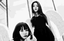 a black and white photo of two women with wings