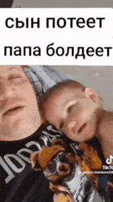 a man and a baby are laying on a bed and the baby has a dog on his shirt